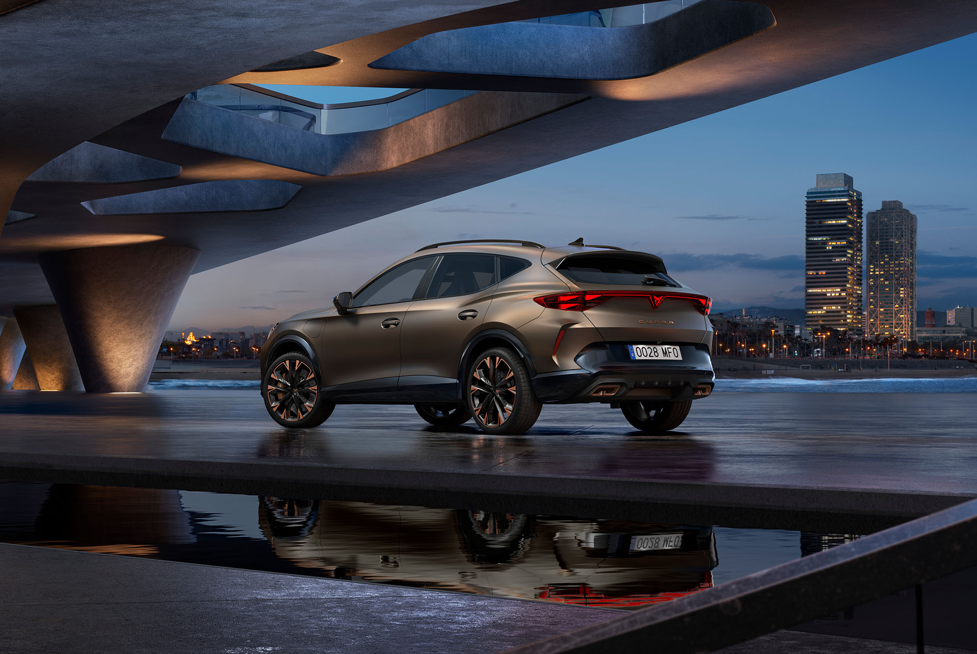Takanäkymä uudesta CUPRA Formentor -hybridiautosta, joka on pysäköity veden ääreen kaupunkisiluettia vasten.